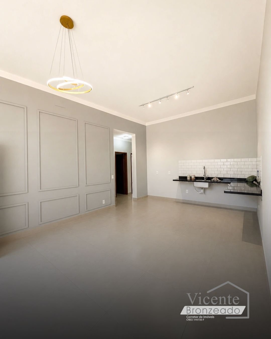 Sala ampla com parede boiserie, lustre moderno e bancada de cozinha em granito preto